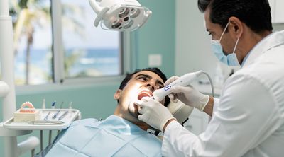 A dentist performs a 3D scan during the preparation phase of a dental bridge procedure.