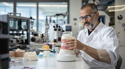 Skilled dental technician carefully crafting custom denture prosthetic in modern laboratory setting.