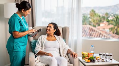 A Mexican nurse monitors a recovering American patient in a Tijuana hotel during mommy makeover recovery.